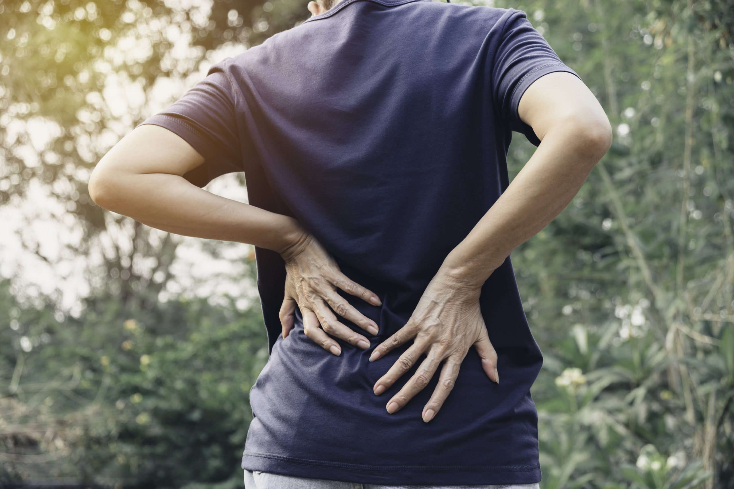 Closeup hands of woman touching her back pain in healthy concept on nature background.